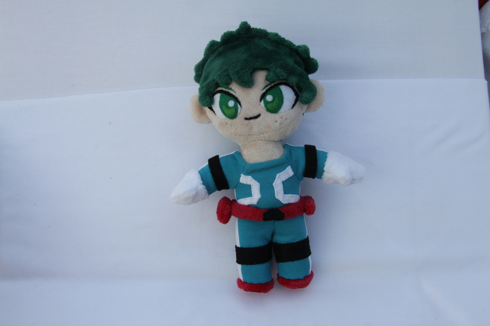 a plush of Izuku Midoriya, a boy with green hair and freckles wearing a blue jumpsuit